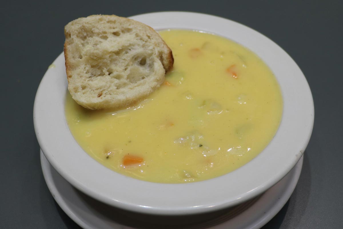 Bowl of creamy california medley soup with a slice of bread.