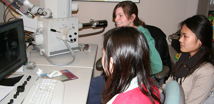 Department of Crop Sciences students Sumin Kim (at left) and Stella Kim (in rear) receive instructions from Cate Wallace of the Microscopy Suite on how to use the facility’s scanning electron microscope.
