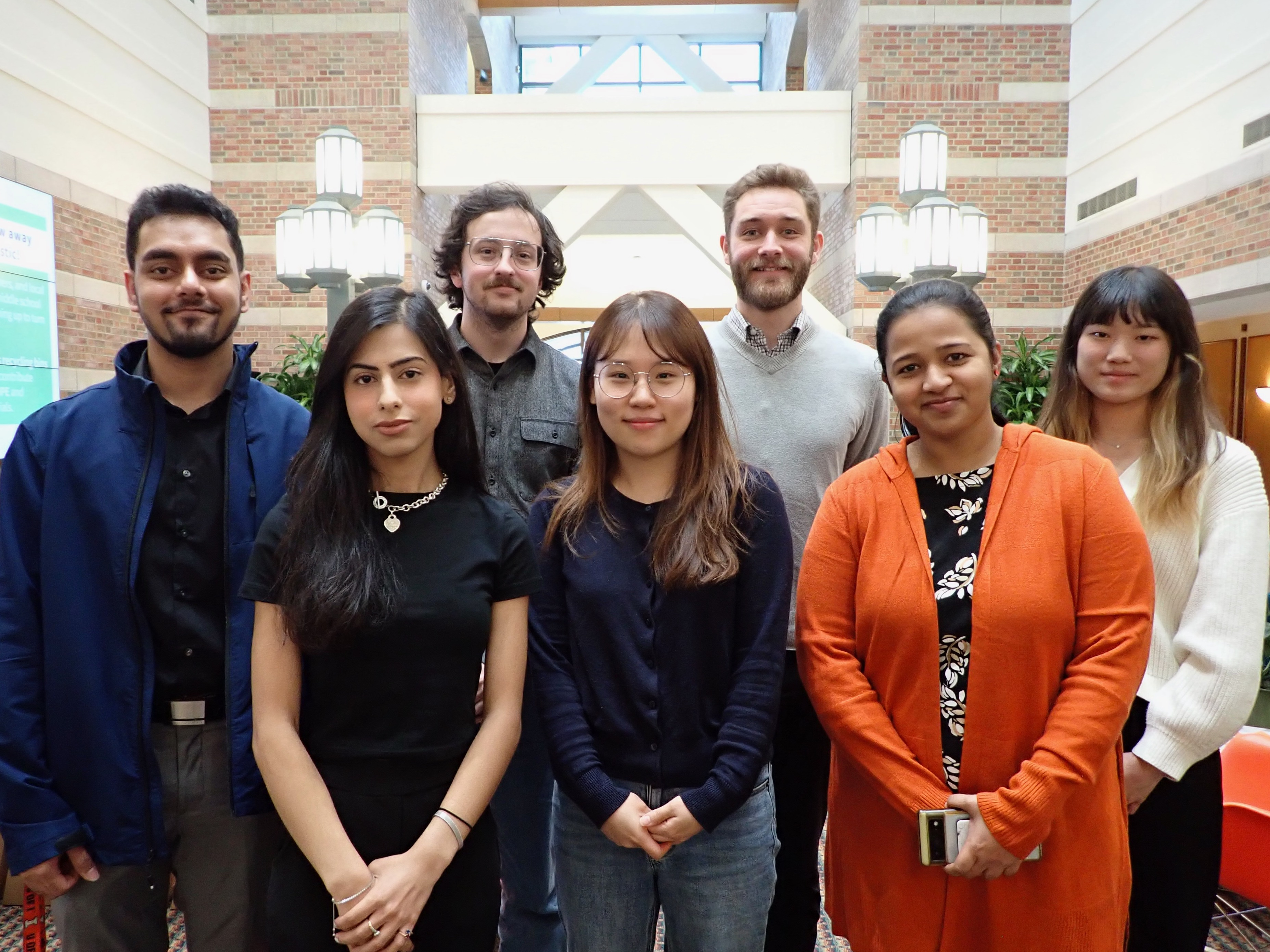 The group of seven Beckman Institute Graduate Fellows standing inside the Beckman Institute atrium.