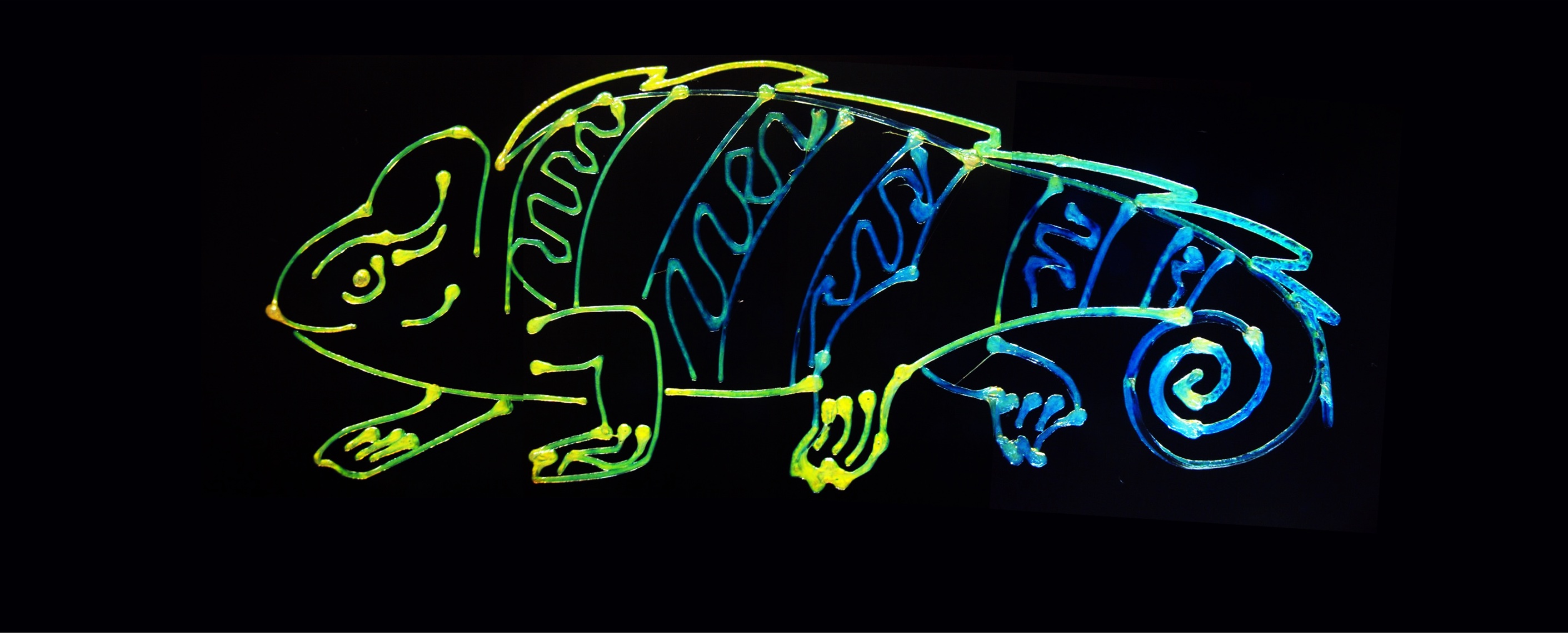 A 3D printed illustration of a chameleon on black background. Color gradient shifts from orange (at head) to blue (at tail).