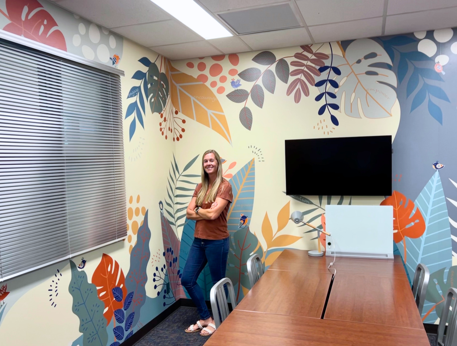 Lindy Carlisle stands in front of the floral-patterned mural in the (dis)Ability Design Studio