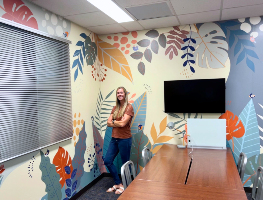 Lindy Carlisle stands in front of the floral-patterned mural in the (dis)Ability Design Studio