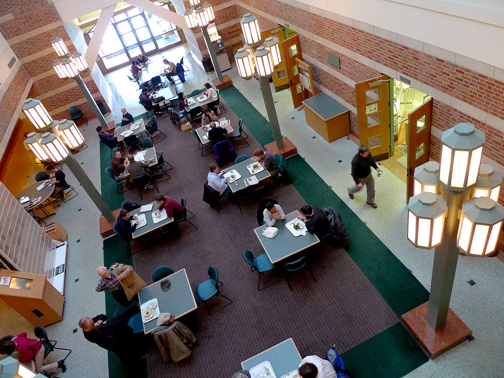 An aerial view of the Beckman Institute Café shows bustling tables of students, faculty, and staff members eating, talking, and collaborating.