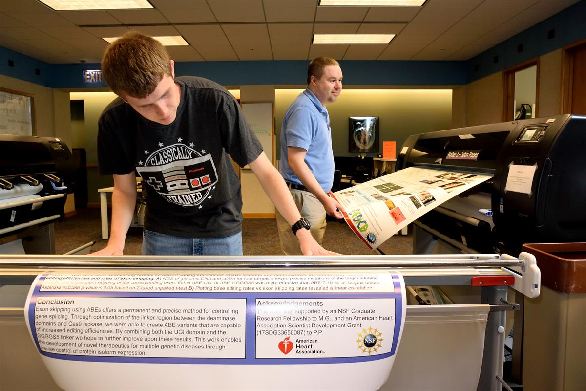 An Internet Technology Services employee helps a student print a poster at the Beckman Institute