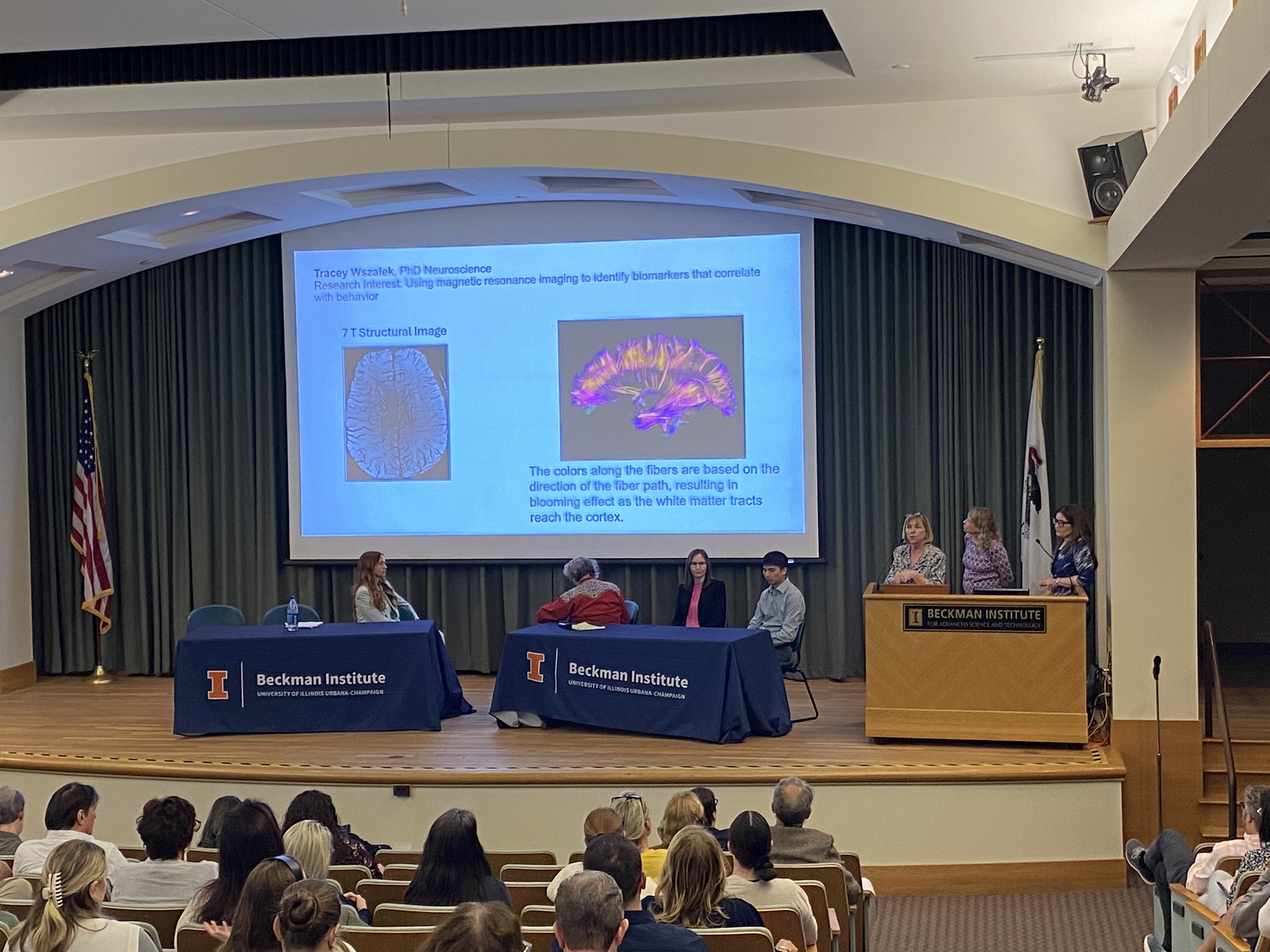 Wszalek, Ceman and Hetrick present their work standing at a podium; the panelists, including commentator Temple Grandin, listen and look at the group's slides.
