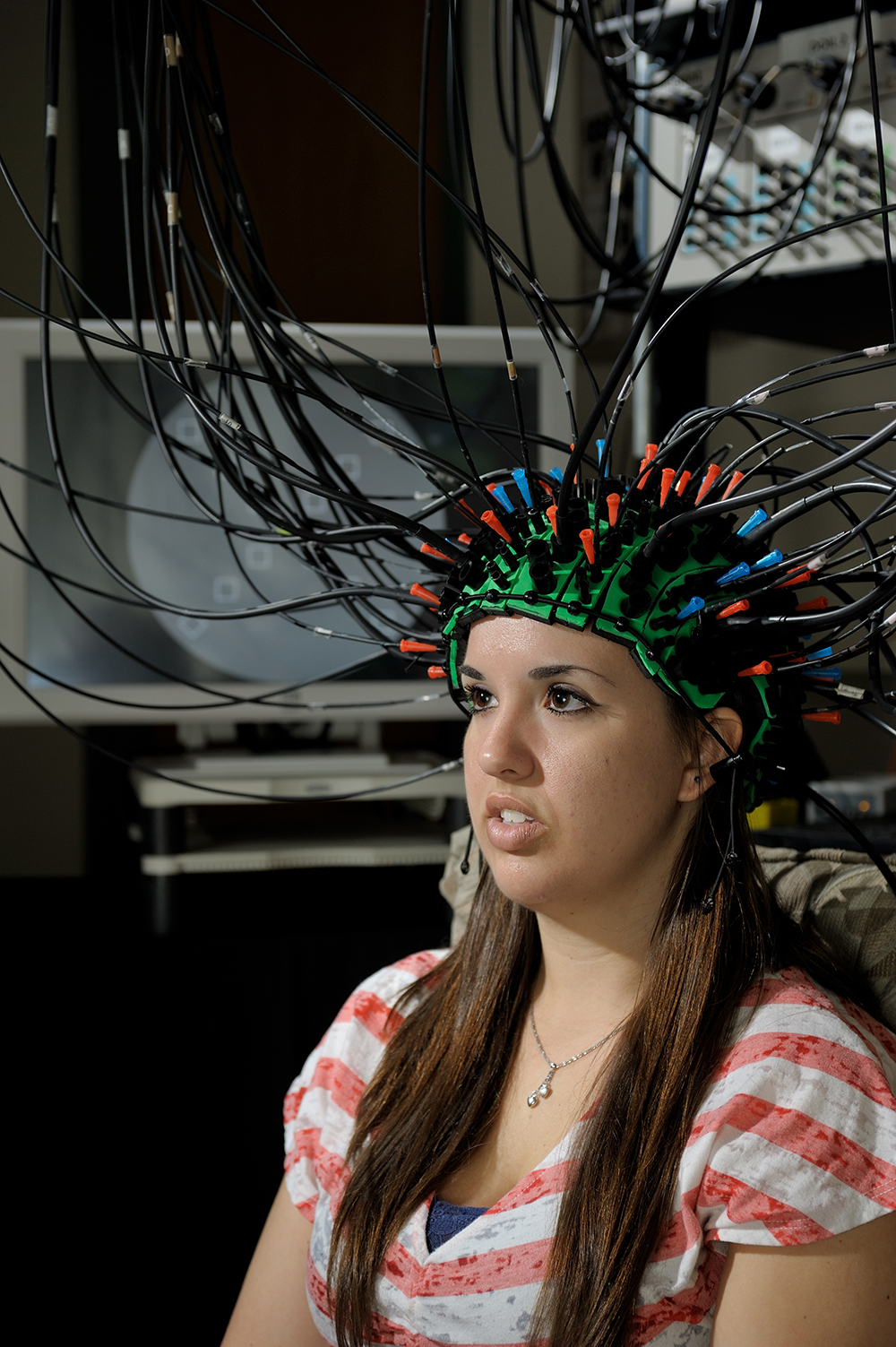 A student wears a cap connected to wires, the Pulse-DOT imaging technique.