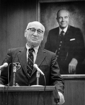 Arnold Beckman stands at a podium, speaking into three microphones, when announcing his $40 million gift to found the Beckman Institute.