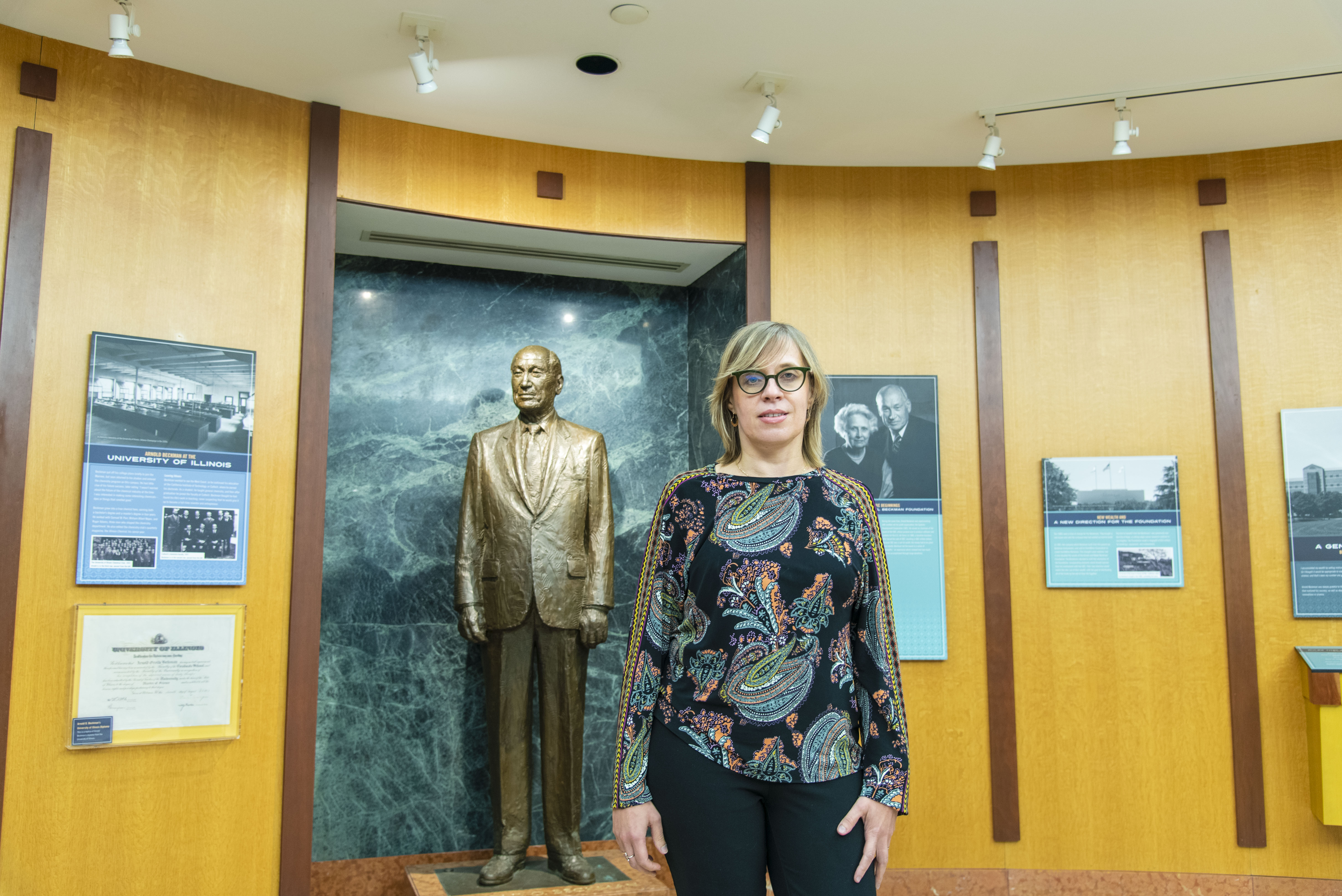 Luisa Ciobanu stands in front of the statue of Arnold O. Beckman in Beckman Institute.