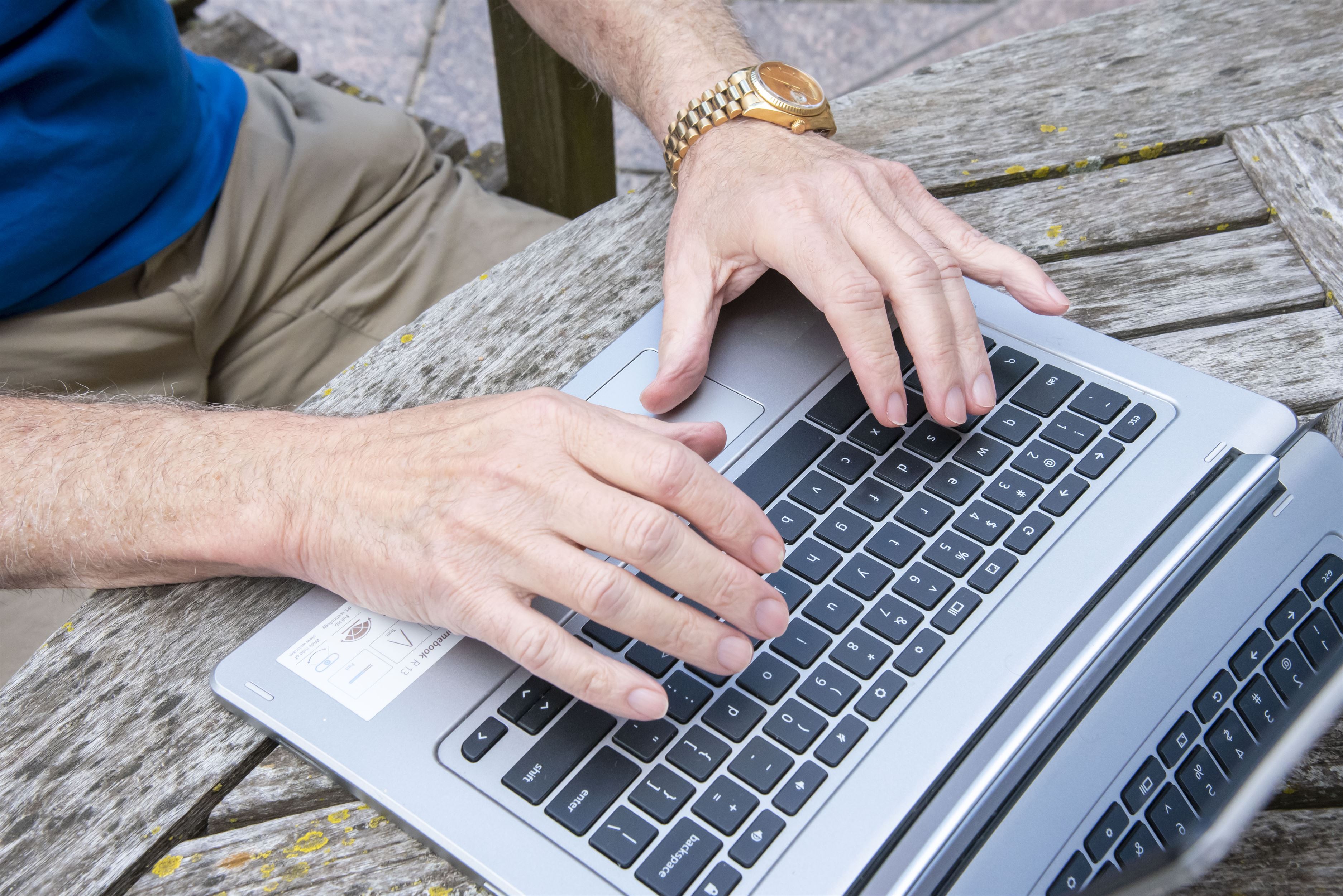 Close-up of a person's hands typing on a laptop keyboard.