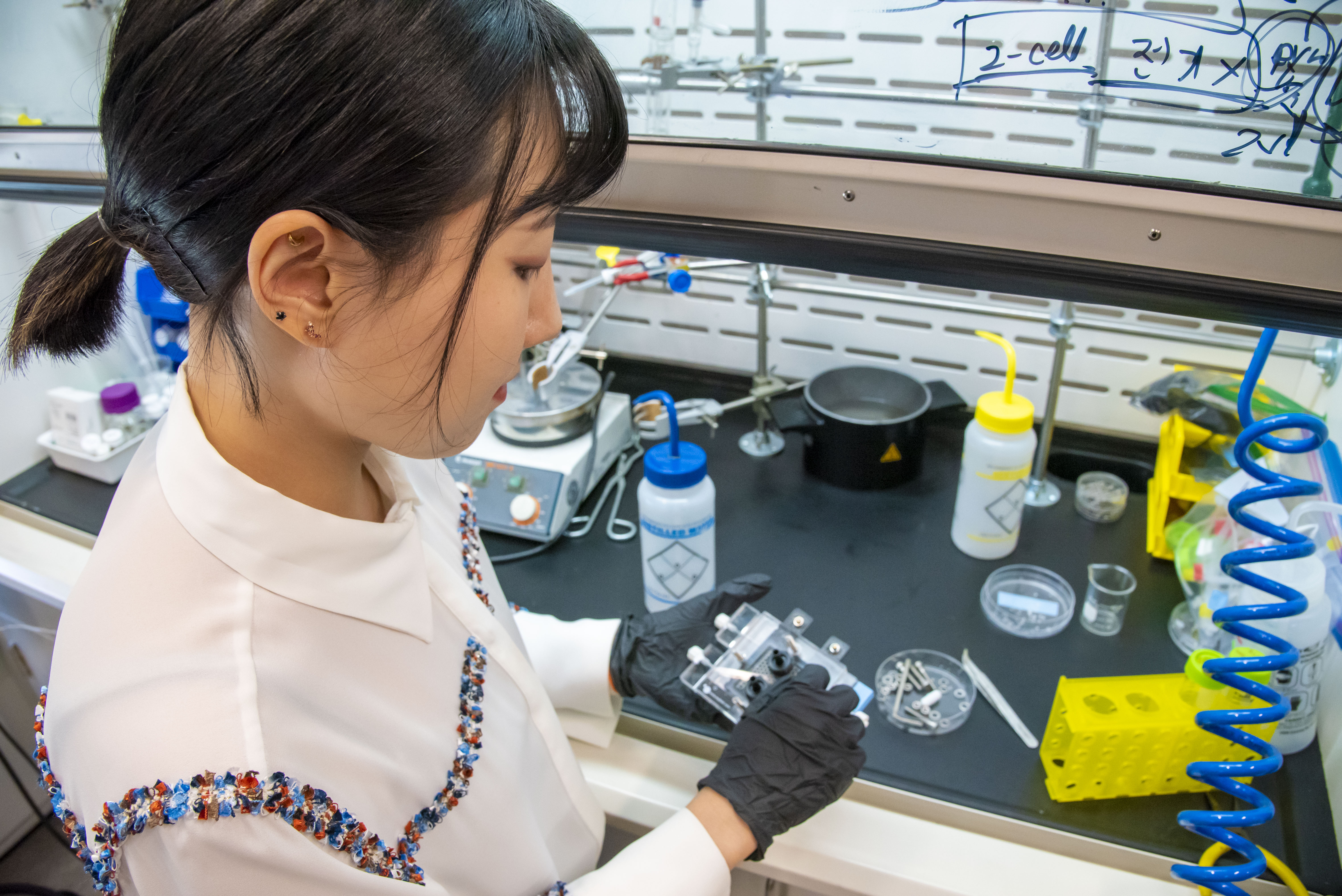 Close-up of a researcher holding a device in gloved hands.