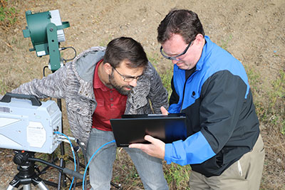 Travis Ross, the manager of the Visualization Lab, consults with John M. Huhn to fine-tune the settings for the high-speed video camera. Huhn is the general manager of Motion Engineering Company, which sold the camera to the Vis Lab.