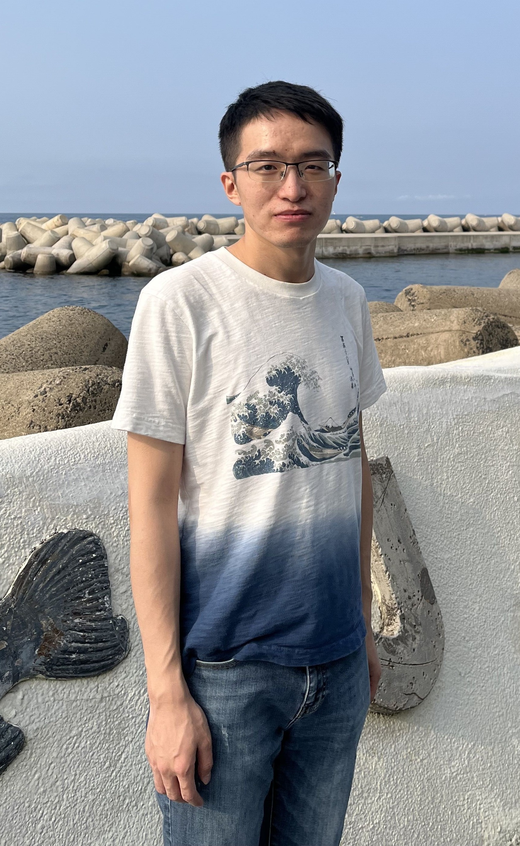 A photograph 2024 Beckman Postdoctoral Fellow Xiao Huan standing in front of a jetty in the water.