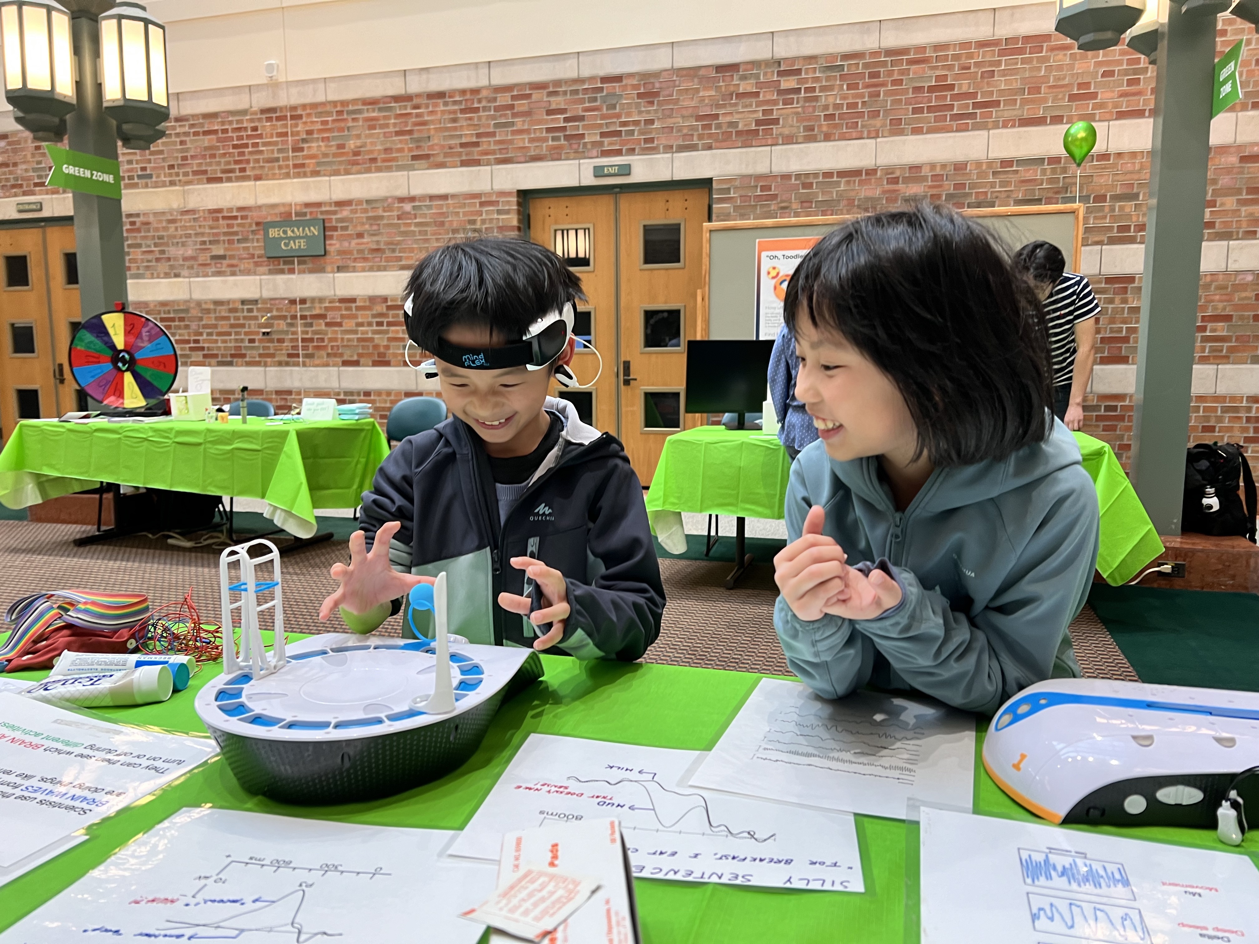 Two children at a science exhibit, watching a ball floating in the air.