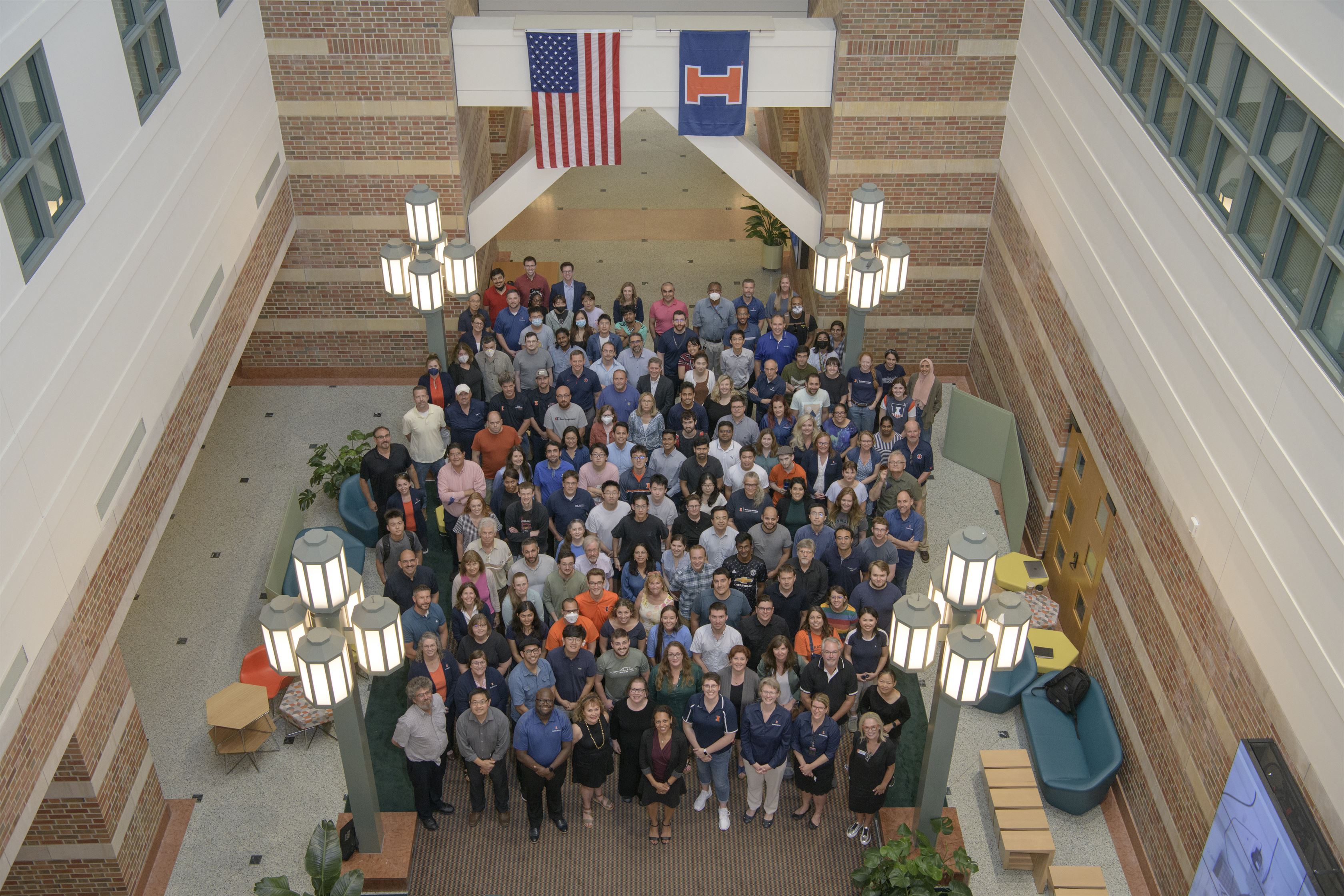 A view of Beckman staff members standing in the atrium, as taken from a bridge, at the Beckman Institute at the University of Illinois at Urbana-Champaign (UIUC)
