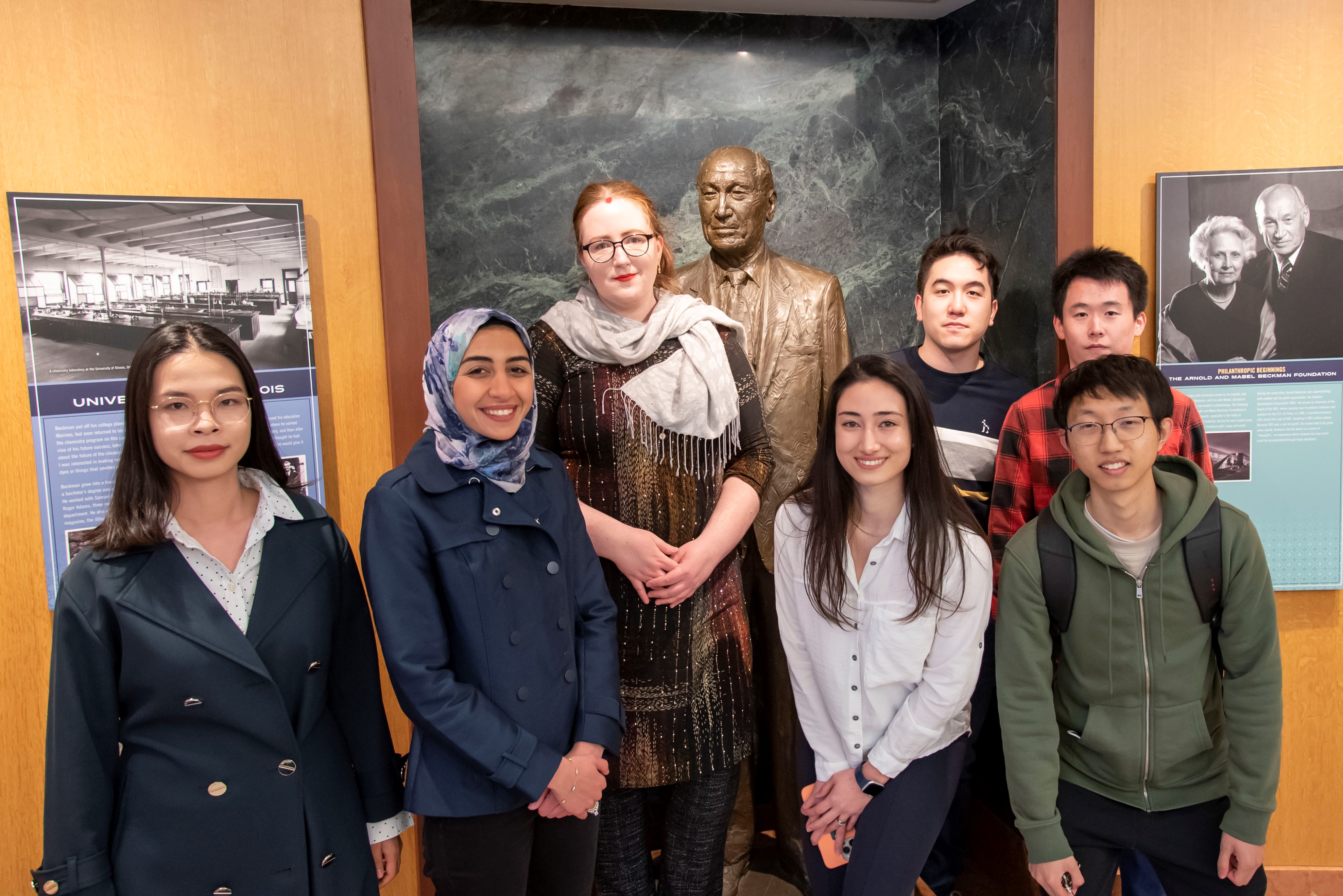 The 2022 cohort of Beckman Institute Graduate Fellows pose for a photo with a statue of Arnold O. Beckman.