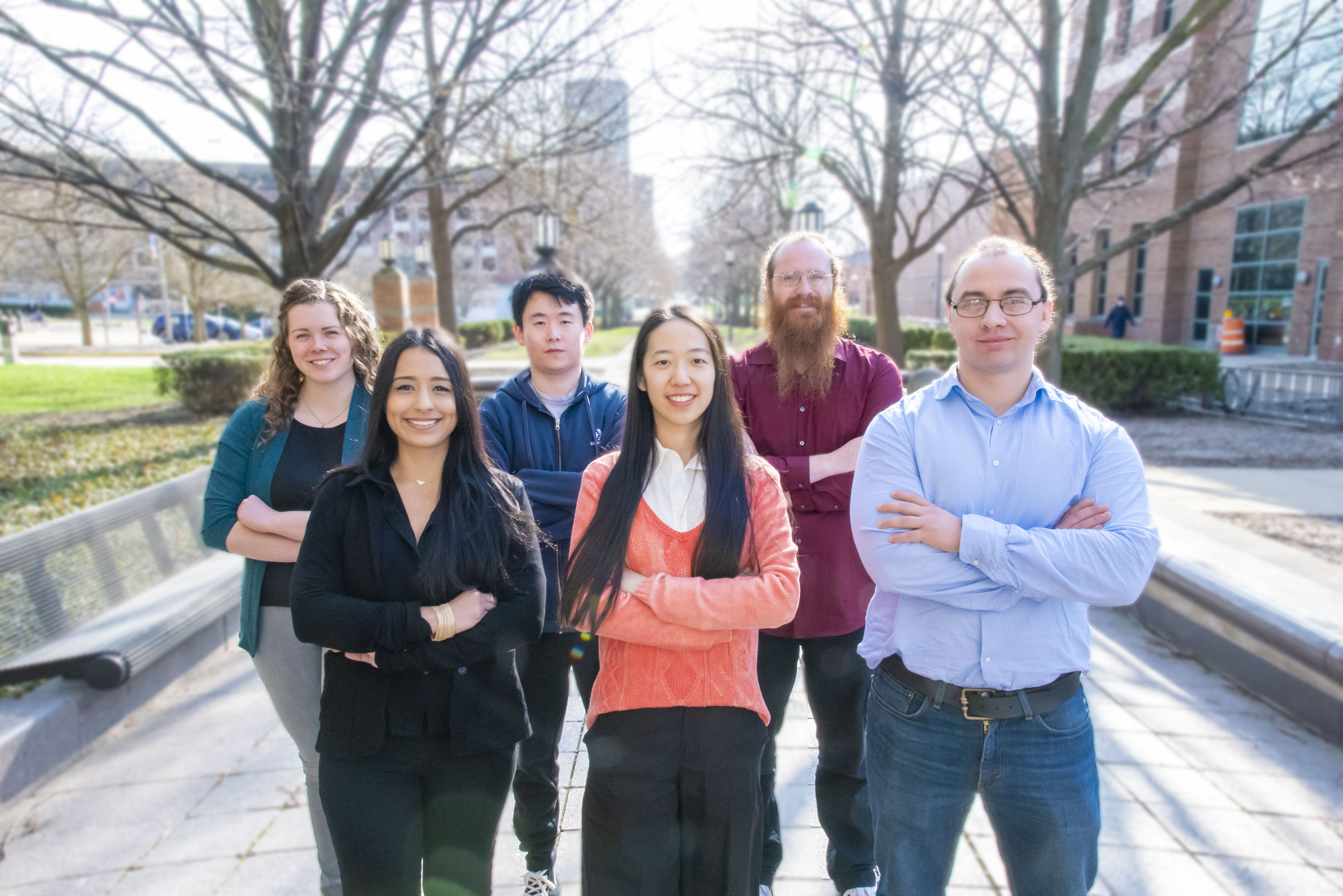 Beckman's six 2023 postdoctoral fellows posed in a group photo outside the institute. The background is blurred.