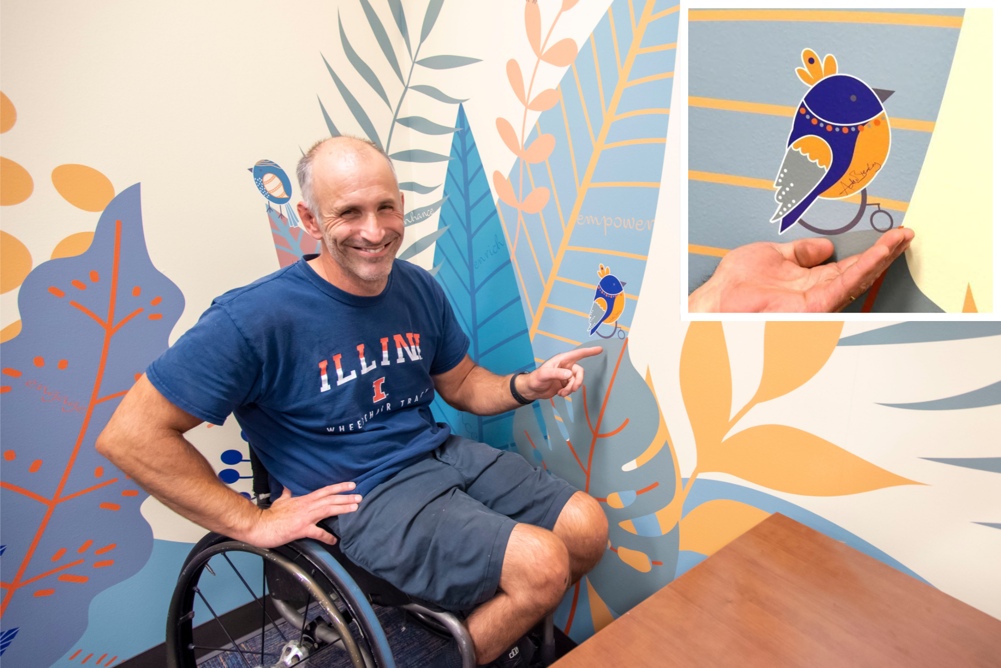 Adam Bleakney points to an element of the (dis)Ability Design Studio's wall mural that represents a small bird using a wheelchair. His signature is on the bird's wing.