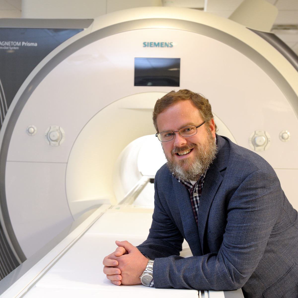 Professor Brad Sutton poses in front of an MRI scanner