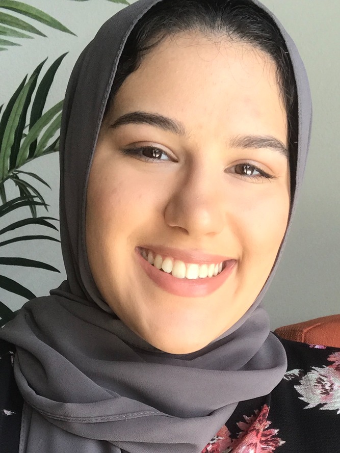Dema Abdelkarim, a smiling woman with brown hair and a mauve headscarf.