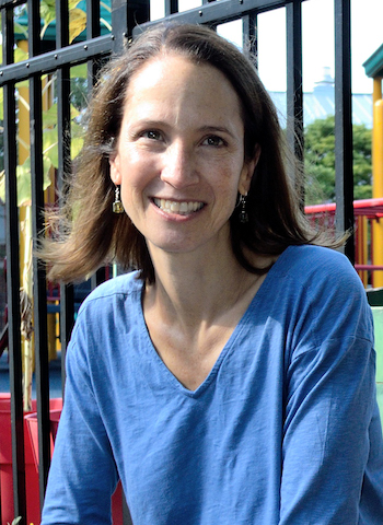 Nancy McElwain, a smiling woman with shoulder-length brown hair wearing a blue long-sleeved shirt.