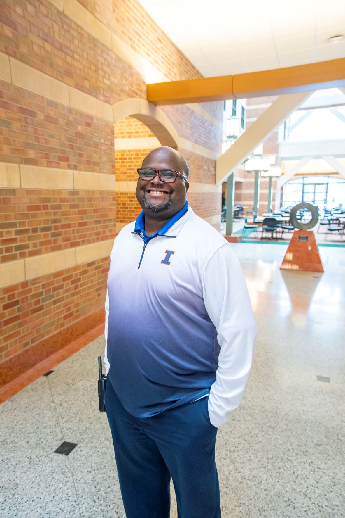 Patrick Holmes stands in the Beckman Atrium wearing Illini gear.