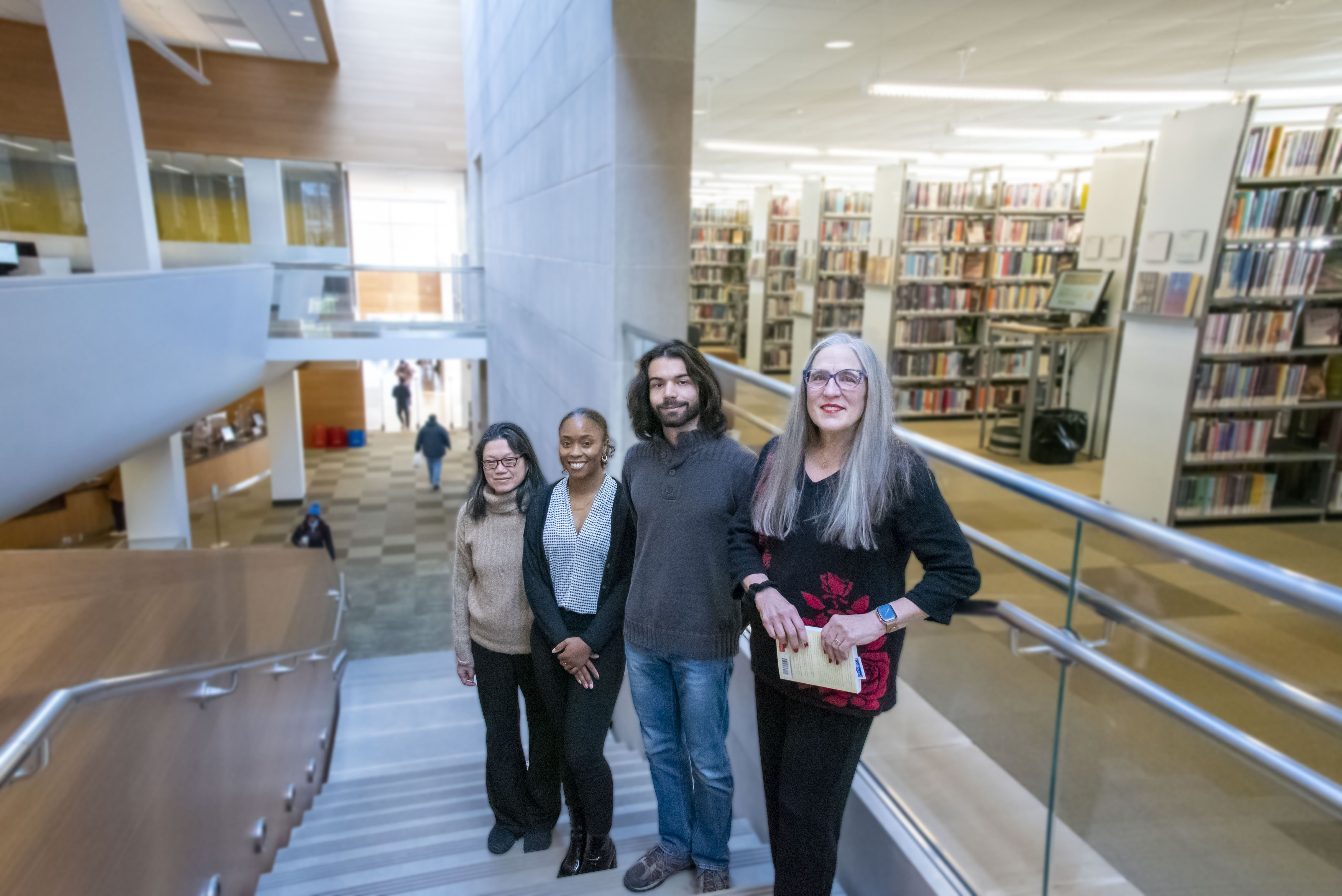 Researchers Liz Stine-Morrow, Giavanna McCall, Ilber Manavbasi, and Shuk Han Ng stand on the stairs of the Champaign Public Library.